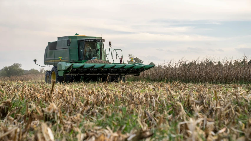 two green machinery are parked next to each other in a field