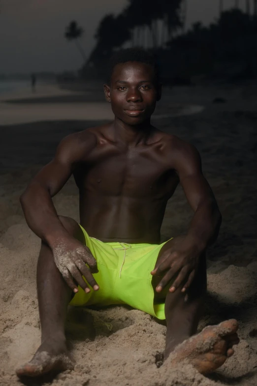 a man in green shorts sitting on a beach