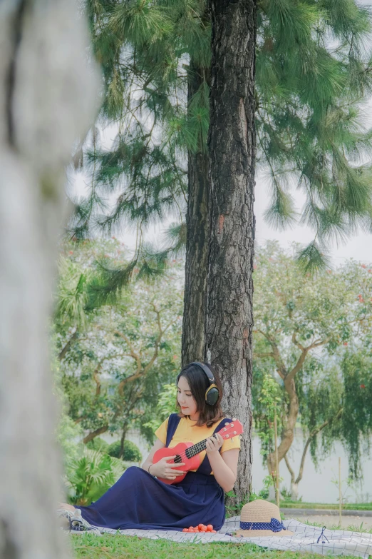 a woman sits on the ground by a tree