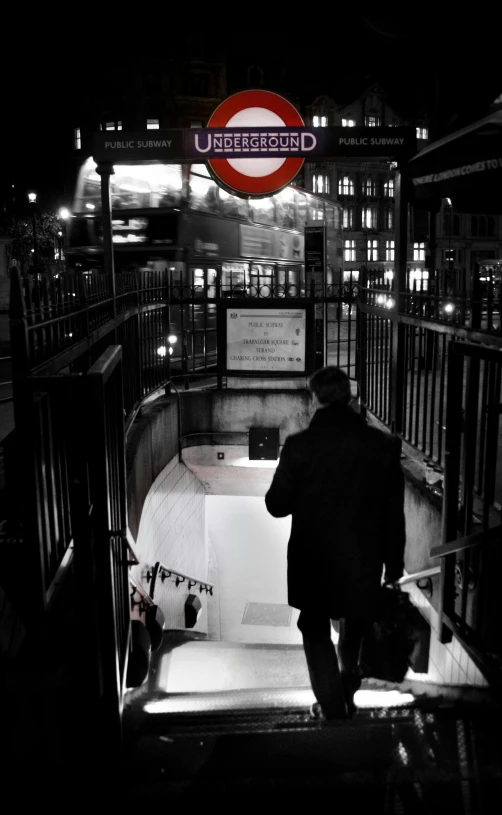 man in long coat walking down the stairs at night