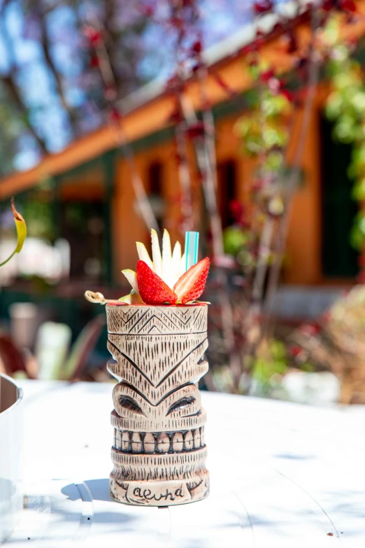 the table with a vase holds an image of a tiki mask