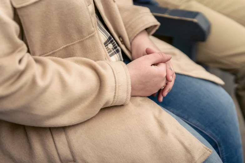 a man in beige jacket holding his hands together