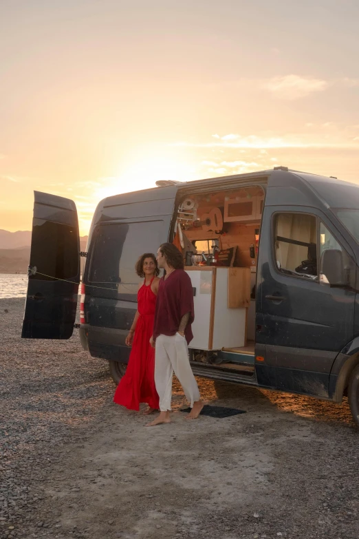 a man and a woman are standing next to the open luggage truck