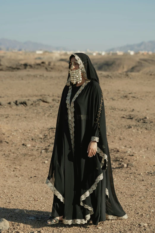 a woman standing in the middle of an empty area wearing a black gown