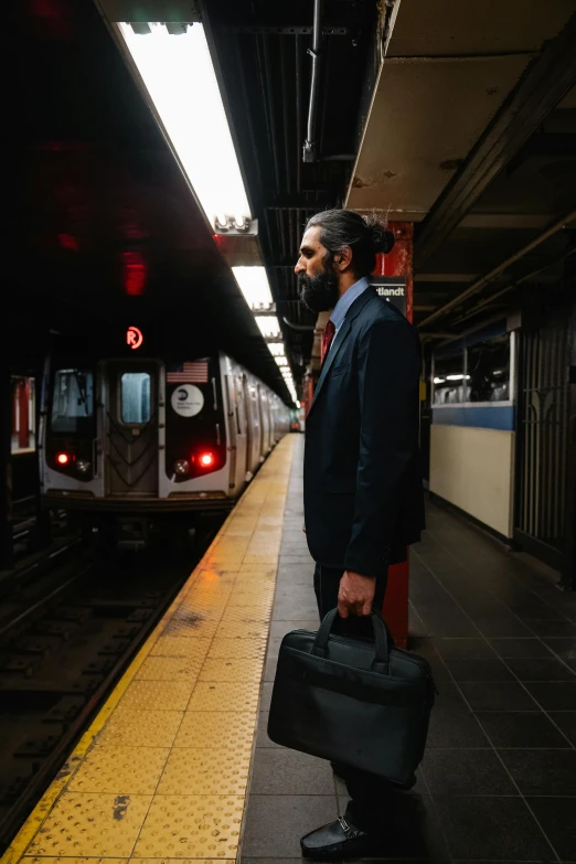 the man has a briefcase waiting for his train to arrive