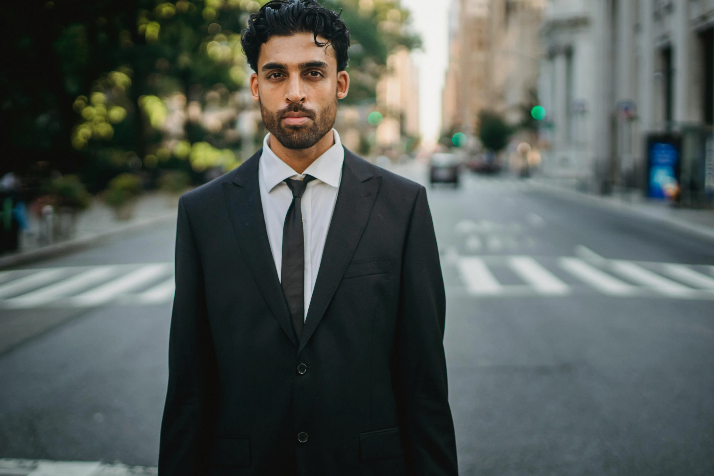 man in black and white suit in street with trees