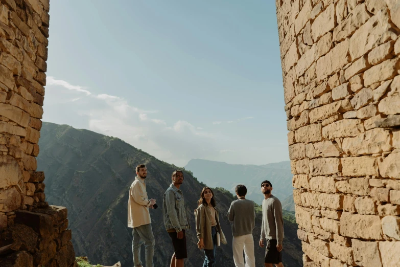 a group of men standing next to each other near a stone wall