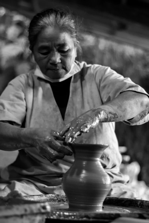 a woman working on pottery with a vase in front