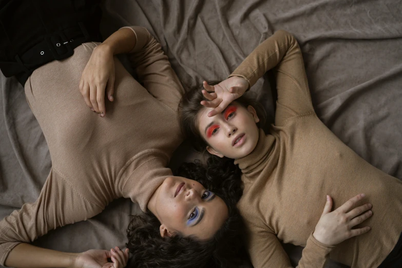 two women laying on a bed in tight clothes