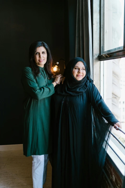 two women wearing green dresses are standing next to each other