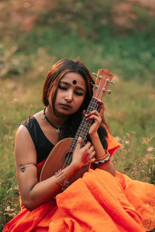 a woman sits on the ground and plays an instrument