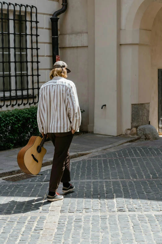 a man walking across a street holding a guitar