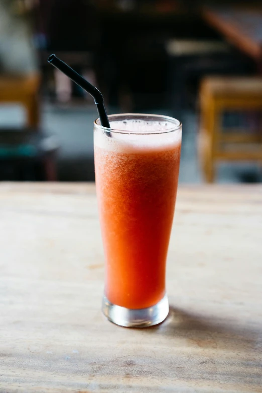 a red drink with a black straw in a glass