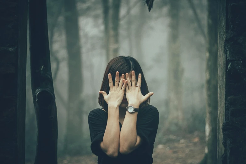 a person in a black shirt covers their face and hands