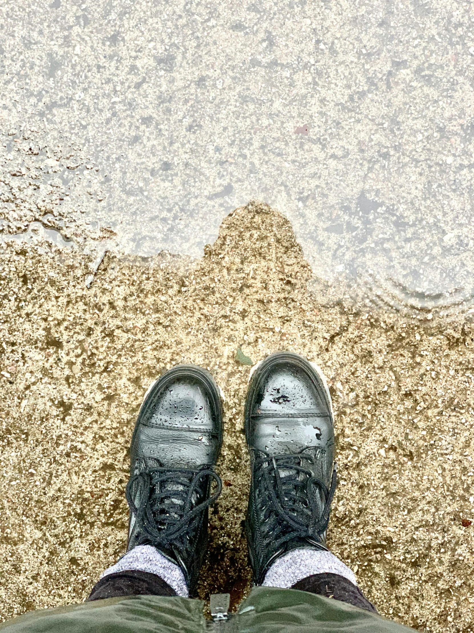 the bottom of someones shoes while standing in front of a lake