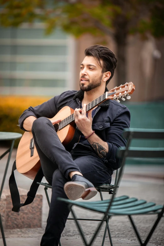 a man sits in a chair while playing the guitar