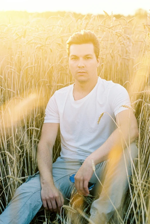 a man sitting in tall grass near some trees