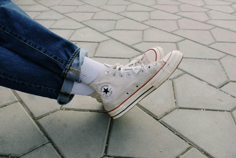 someone is sitting on the cobblestones with his sneakers