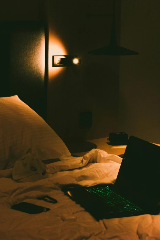 an illuminated computer on top of a unmade bed