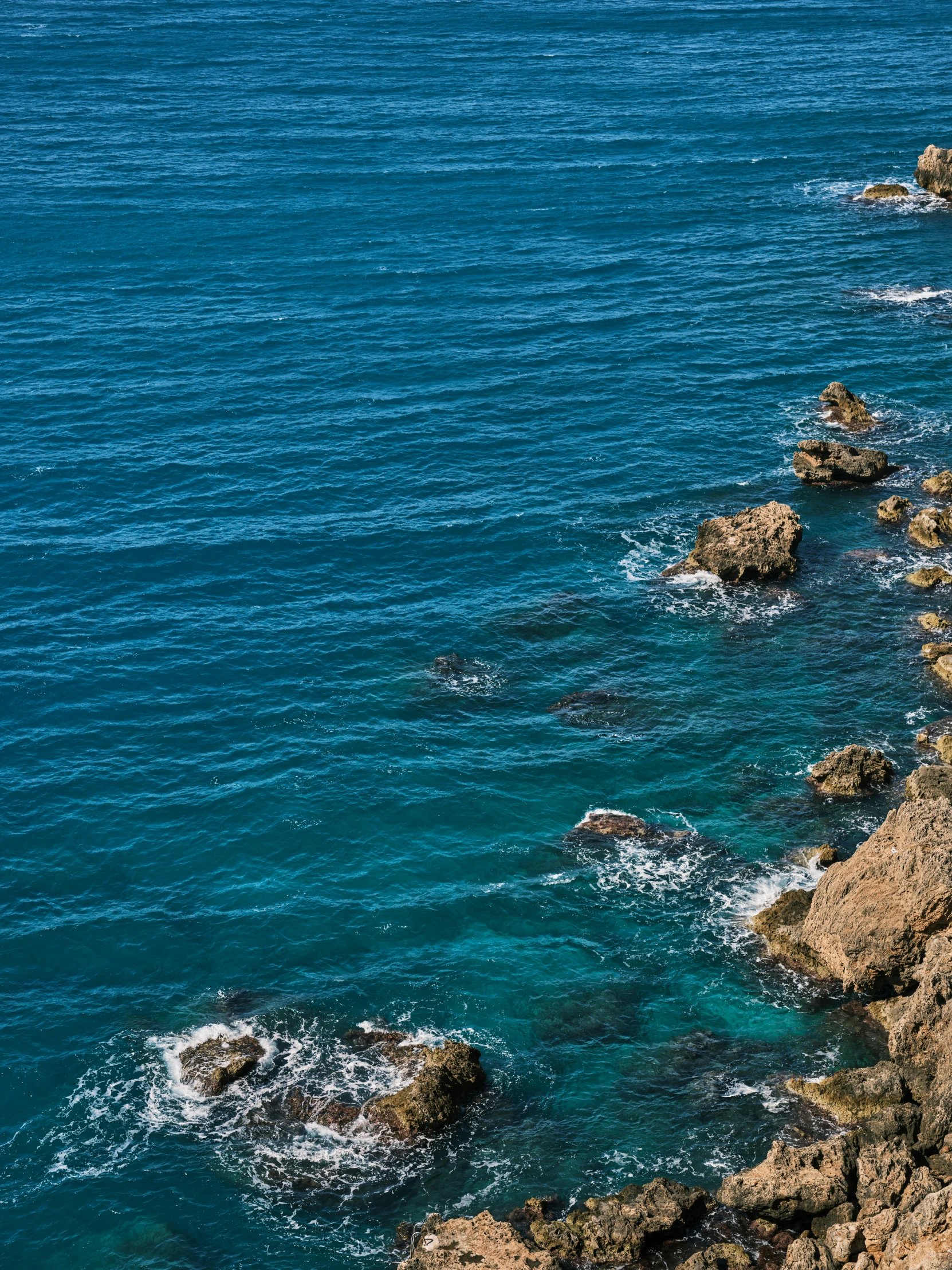 the ocean with a rocky shore and cliffs around