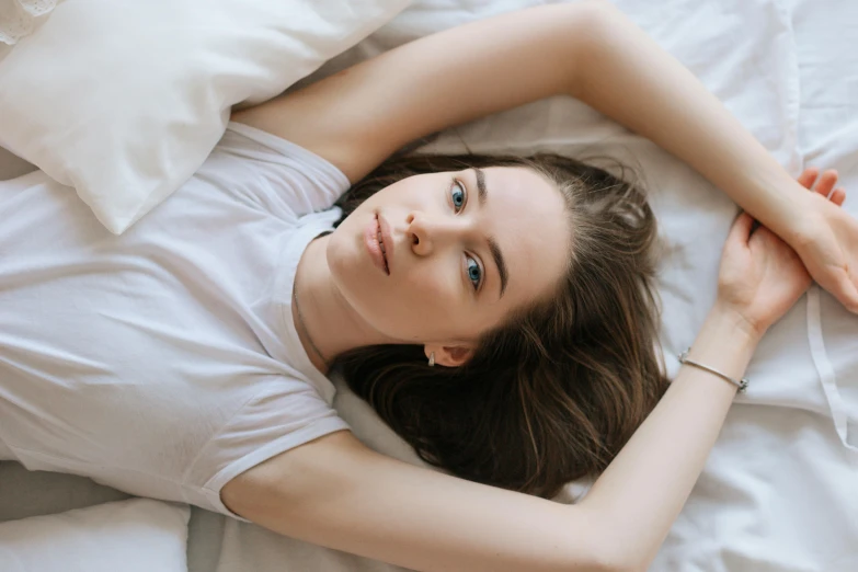 a woman is sleeping in a white bed