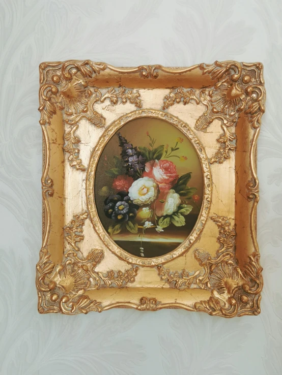 painting of flowers in a golden frame on a wall