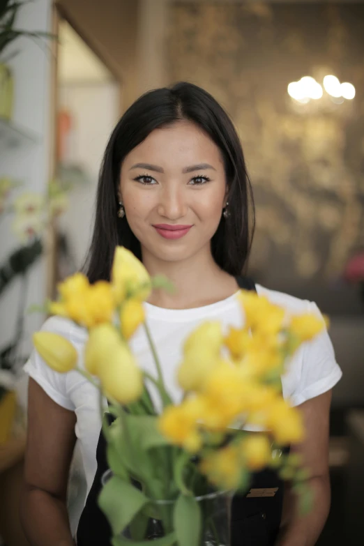 a young woman holding a bouquet of yellow flowers