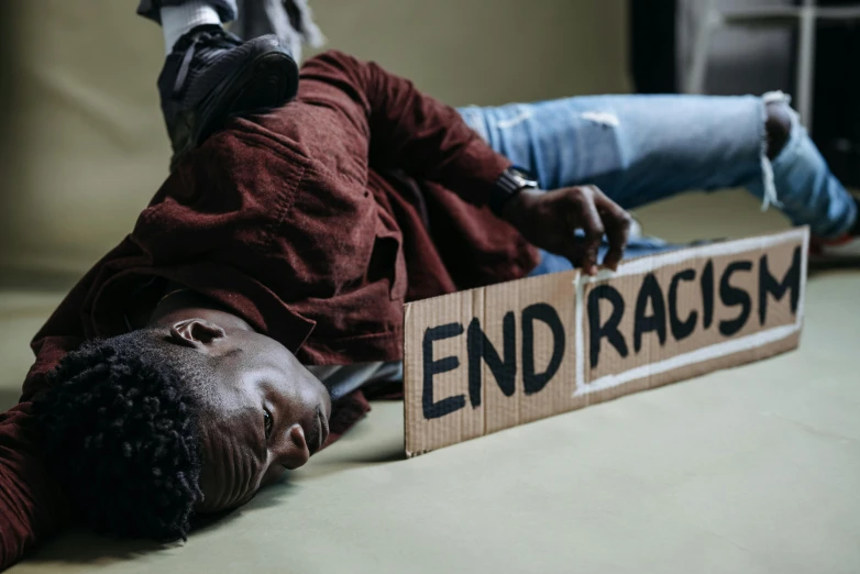 an individual lying on a floor with an end racism sign