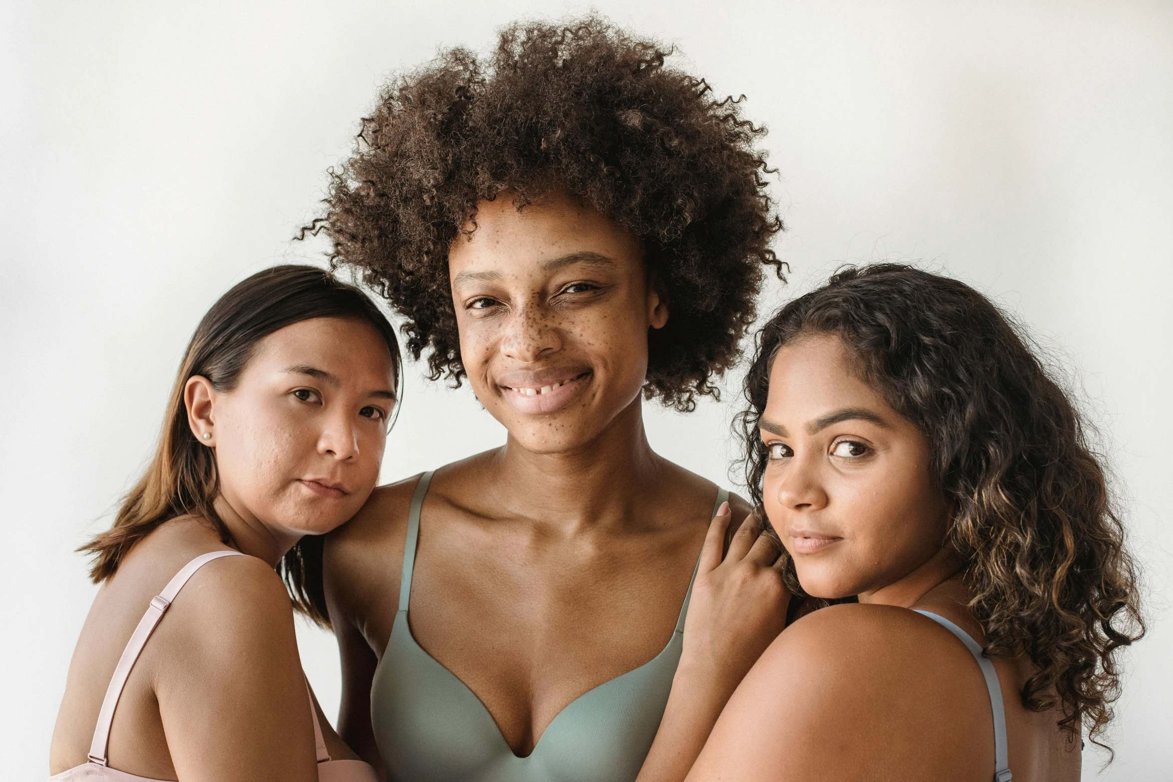 three young women are standing together wearing  tops