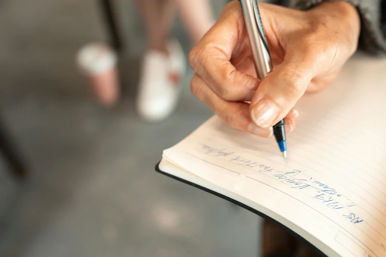 a person writing with a pen on top of a piece of paper