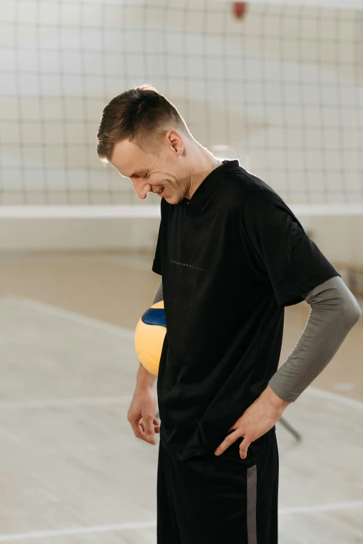 a man standing on a court holding a volley ball