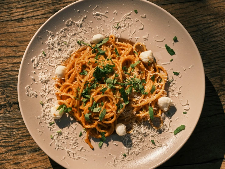 a white plate with noodles and carrots on a wood table