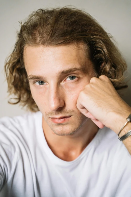 young man with white shirt and his hand on his head