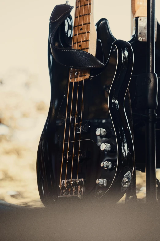 a black bass guitar is against a brown backdrop