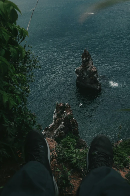 a person standing on a mountain with his feet up looking at the ocean