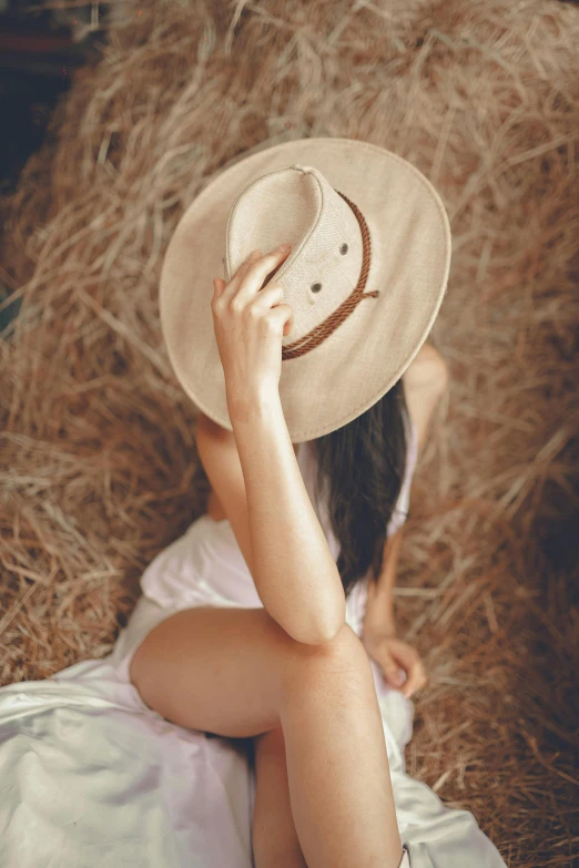 a woman laying on a bed of hay with her hands behind her face