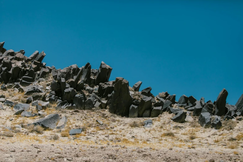 several very large rocks and bushes on a hill