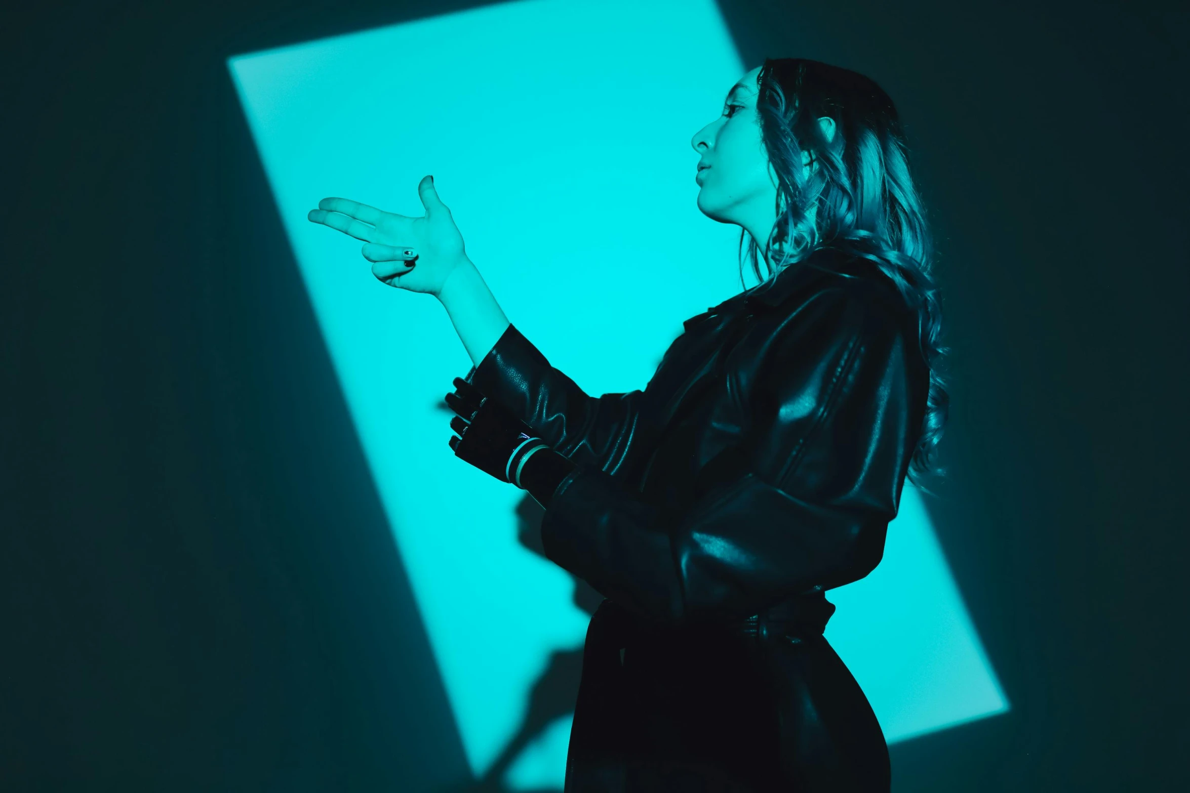 woman in leather coat with hands open looking to a screen