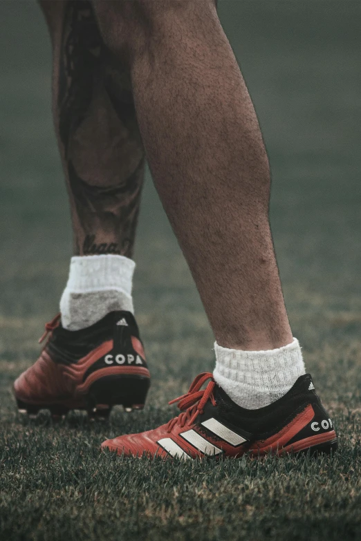 the legs of soccer players who are in red and black shoes