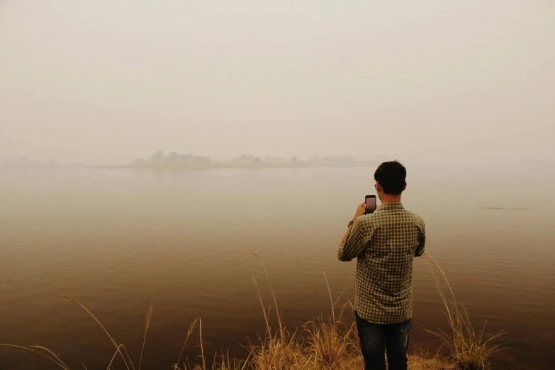 a man is taking a picture of a body of water with his cellphone