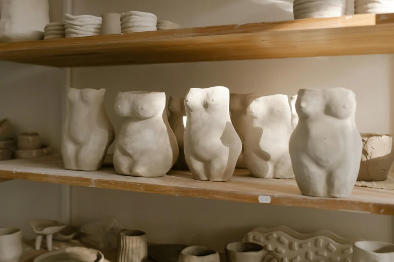 several white ceramic figurines sit on a wooden shelf