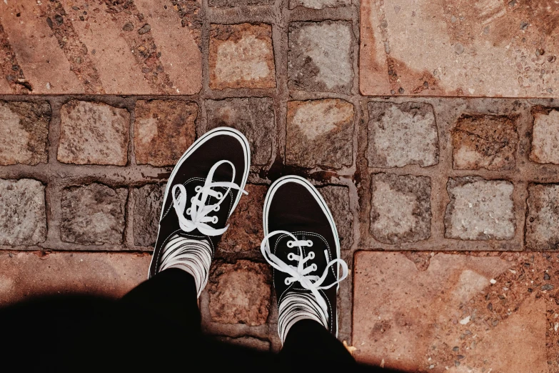 a black and white vans sneakers on some bricks