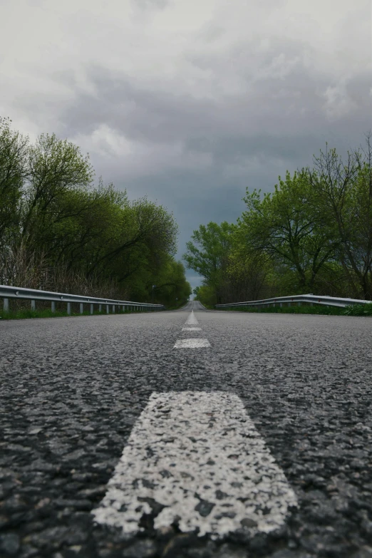 the road is surrounded by benches and trees