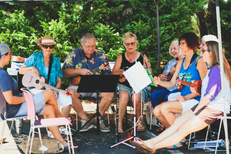 a group of people sit in chairs under an awning, listening to music