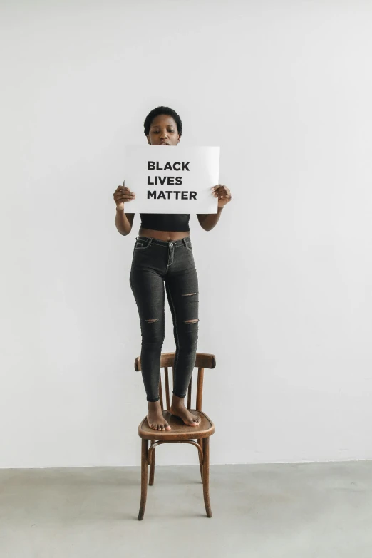 an african american woman holds up a sign and sits in a chair in the middle of a white background