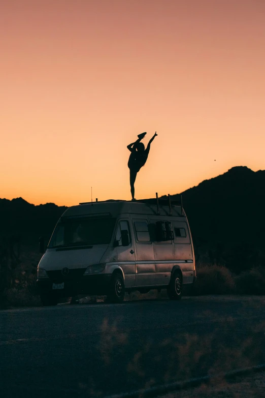the man is standing on top of his van and he's doing tricks
