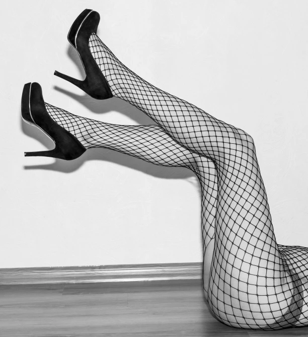 a woman in fishnet stockings and high heels laying on the floor