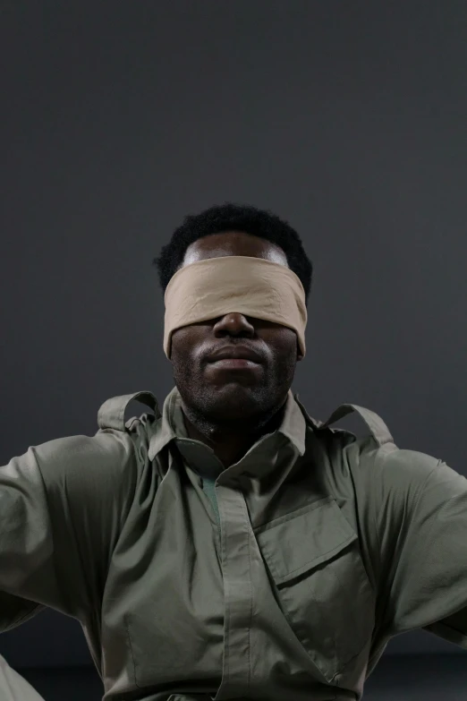 a man in military clothing wears a blindfold