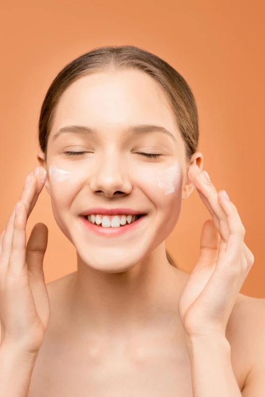 a young woman smiles as she holds her hands up to her face