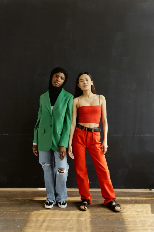 two women are standing next to a wall